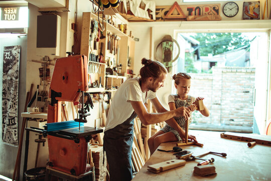 Father teaching daughter woodworking in home workshop