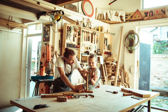 Father and daughter woodworking together in home garage workshop