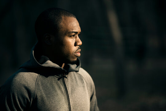 Profile portrait of focused male runner in gray hoodie outdoors