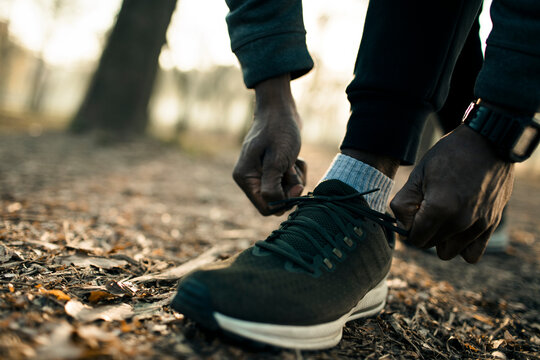 Runner tying shoelaces on forest trail at sunrise