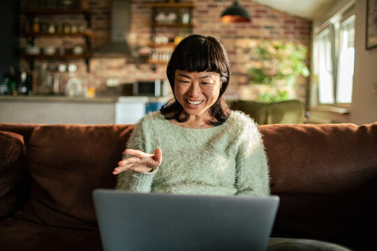 Smiling woman video chatting on a laptop at home