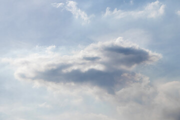 Obraz premium Cloudy sky with a large dark gray cloud in the center and light white clouds around, soft daylight, calm atmosphere