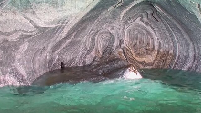 Gaze upon the mesmerizing Marble Caves in Patagonia, where pristine azure waters gently ripple against swirling, sculpted rock formations. A testament to nature's profound artistry.
