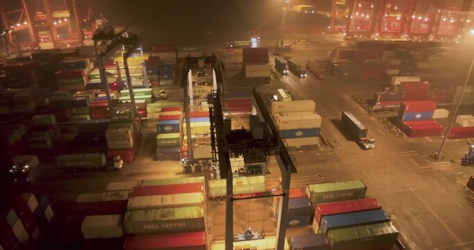 Busy Container Port at Night with Cargo Cranes and Trucks