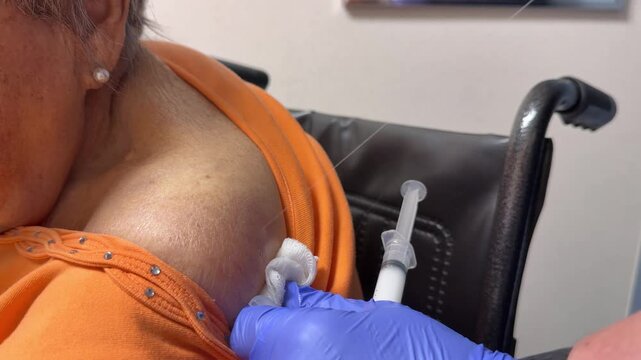 Close-up of an elderly woman in a wheelchair receiving a cortisone injection in her shoulder for arthritis pain and joint inflammation treatment. 15128