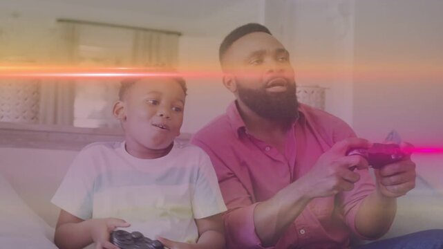 Dad and son gaming on sofa, boy pressing pad celebrating win as pink-orange flare overlaying scene