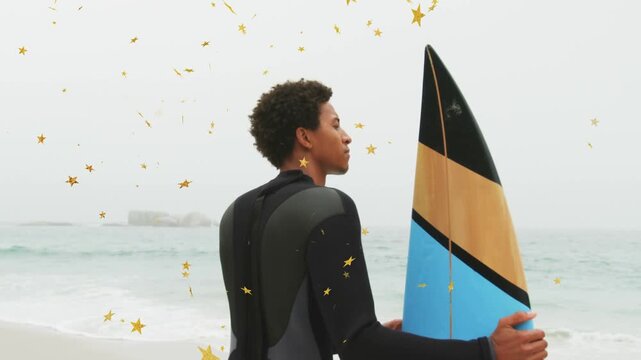 Surfer scanning sea, adjusting grip, preparing to surf with gold stars drifting around him, travel