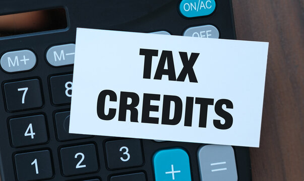 Black note with bold tax credits text rests on calculator