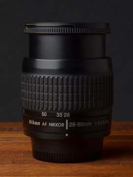 PERPIGNAN, FRANCE - MAY 6, 2026: A Nikon Nikkor 28-80mm f3.3-5.6 G zoom lens on a wooden surface. A compact and lightweight photographic lens for digital and film SLR cameras