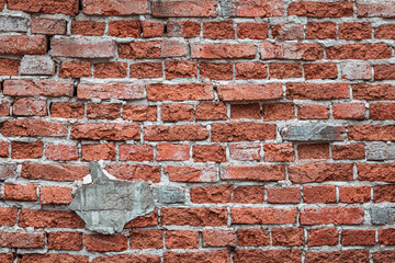 Weathered red brick wall showing crumbling mortar and broken bricks, creating a rustic urban background pattern © EdNurg