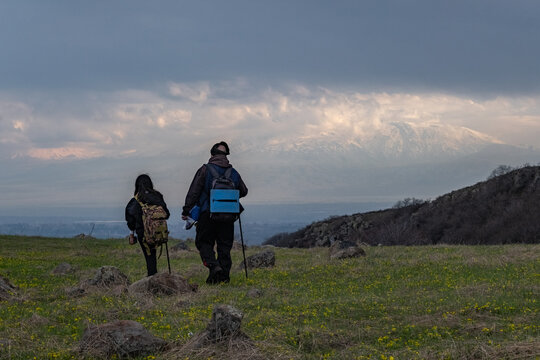 Father and daughter in hiking walk across meadow against background of majestic white snowy mountain peaks. Family hiking with dad. Children interest in travel and adventure. Endurance development