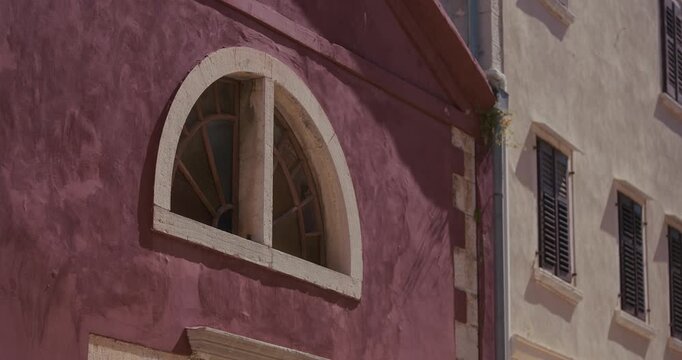 Arched window on colorful old town house facade with shutters in Rovinj, Croatia during the morning.