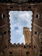 Obraz premium Low angle view of Torre del Mangia tower from the courtyard of Palazzo Pubblico in Siena, Tuscany.