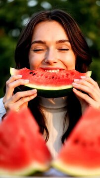Cheerful Young Woman Enjoying Fresh Watermelon holding a juicy red slice outdoors with a bright smile perfect for healthy lifestyle and summer vacation content Vertical. Video. Portrait Orientation.