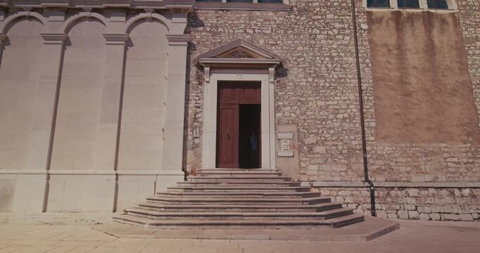 Facade and entrance of the Church of St. Euphemia with stone steps and the bell tower in the old town of Rovinj, Croatia during the afternoon.