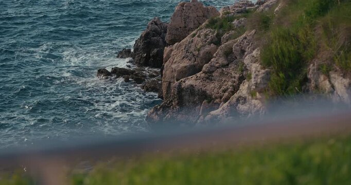 Rocky Adriatic coastline with waves near Baluota Beach in Rovinj, Croatia during the afternoon.