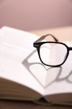 Stylish glasses and book on table, closeup