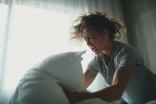 somatic anger release, woman punching pillow at home and screaming, emotional release of rage