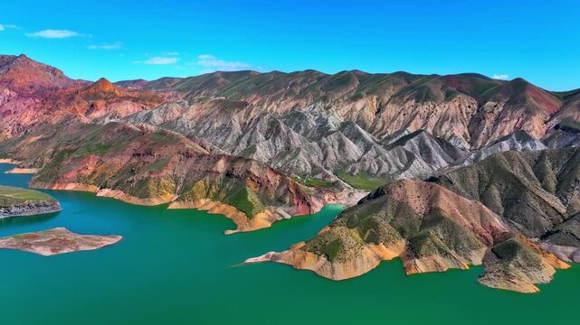 Aerial view of a vibrant turquoise lake surrounded by colorful mountain ranges