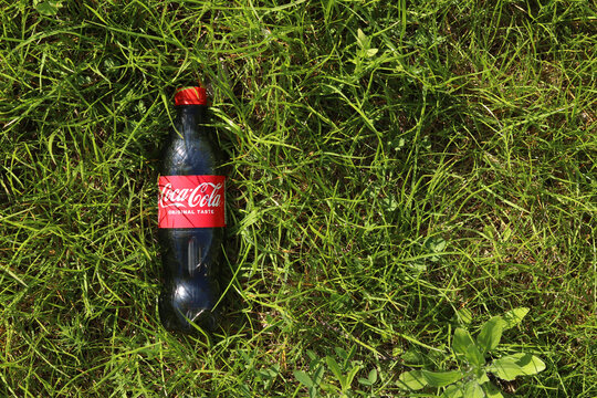 Kyiv, Ukraine - May 6, 2026: Plastic bottle of Coca-Cola Classic drink in green grass, top view. Refreshing Coca-Cola drink on the lawn. Summer picnic, sunny day. Classic 0.5 liter bottle of Coca-Cola