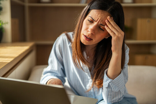 Woman experiencing stress, headache while working from home