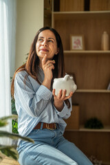 Woman thinking about financial future holding piggy bank © Miljan Živković