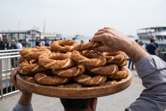 Street vendor carrying a large wooden tray stacked full of fresh simit bread on his head