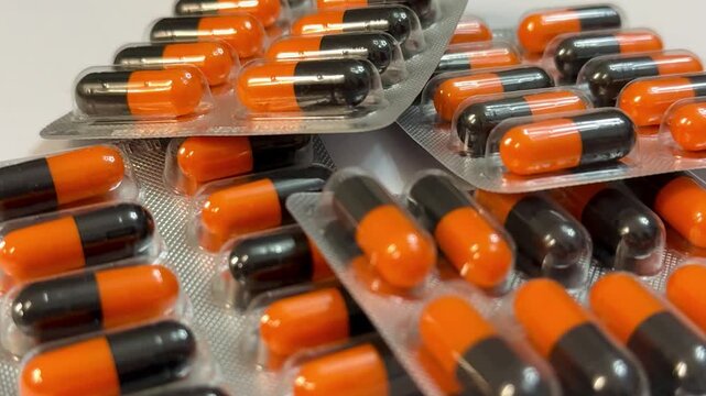 Orange And Black Capsules In Blister Pack, Closeup Showing Glossy Capsules Arranged In Foil Trays, Pharmacy Storage And Packaging Scene With Emphasis On Dosage, Sterile Clinical Lighting