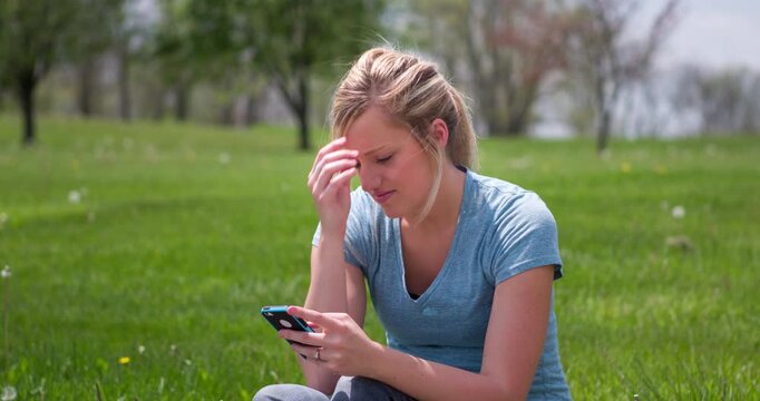 Girl sitting in grass texting 4k
