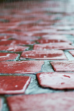 Close-up shot of a worn red brick sidewalk with cracks and imperfections vertical frame