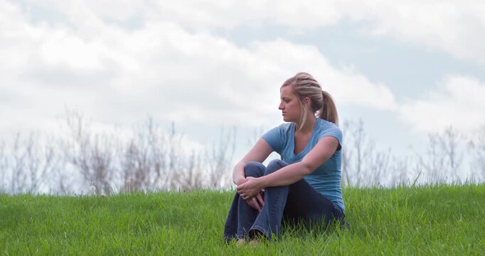 Young girl sitting in green grass 4k
