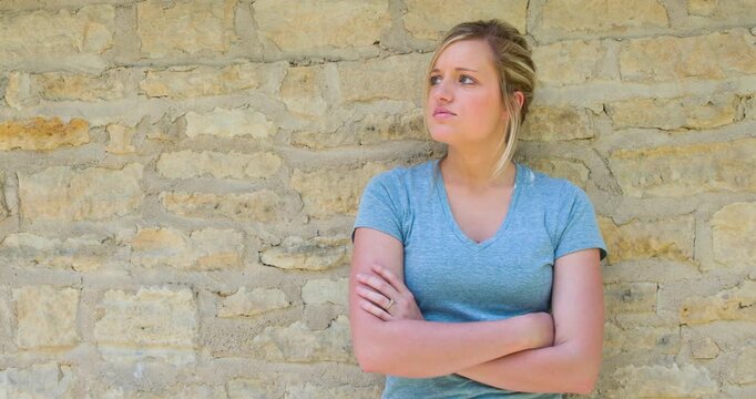 Girl with arms crossed against brick wall 4k
