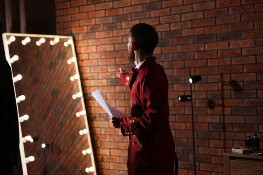 Actor with script rehearsing his lines near mirror in dressing room