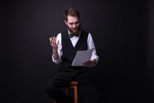 Professional actor with script performing on black background