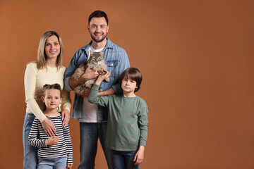 Obraz premium Happy family with their cute cat on brown background, space for text. Adorable pet