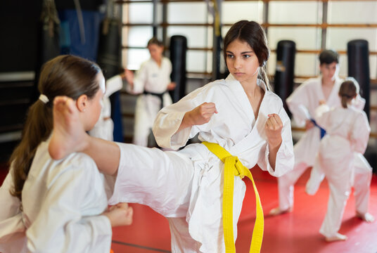 Teenage girls are actively engaged in judo. Children in white kimonos at a martial arts training session