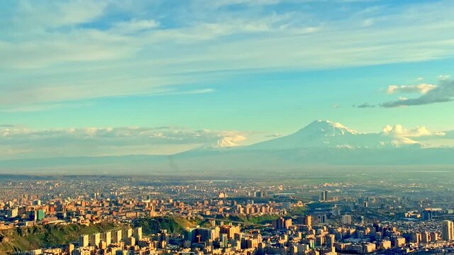 Cityscape with snowy mountain in distance. Buildings stretch across valley