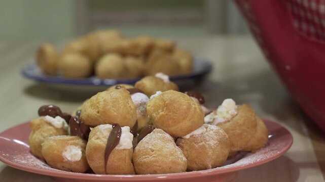 Hand filling delicious profiteroles with cream. 4K