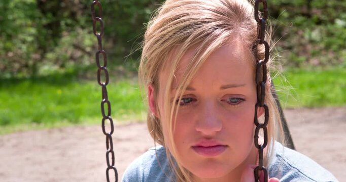 Female on swing sad looks at camera  4k
