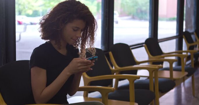 Young girl sitting in waiting area texting 4k
