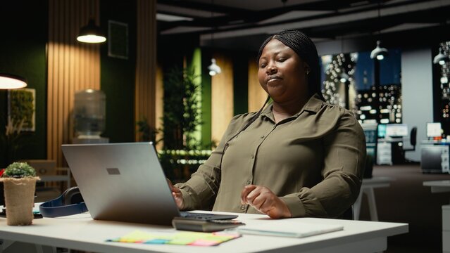 Black consultant focusing on a complex problem in a dark office at midnight, strategizing and envisioning options with laptop open. Seeking a logical solution through careful deduction. Camera A.