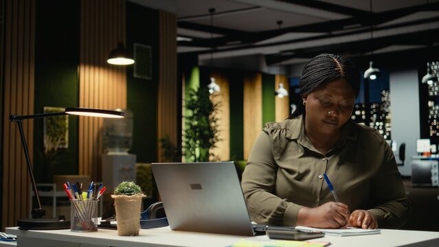 Mad black entrepreneur ripping paper after transcribing key points on notebook after hours, makes a writing mistake and breaks the page from the textbook. Strategy for targets. Camera A.