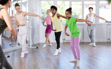 Obraz premium Group of boys and girls teenage dancers performing ballet movements in dance class