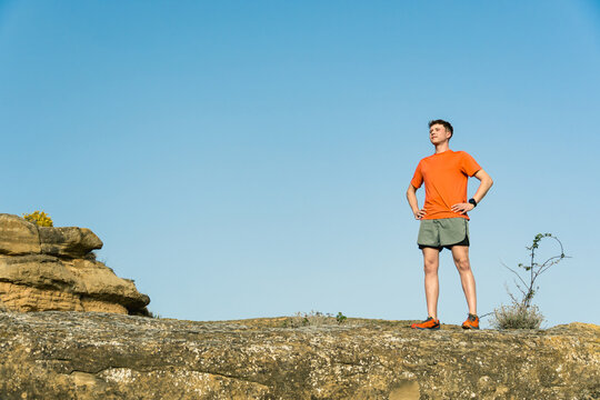 Young man runner standing on rock outdoors