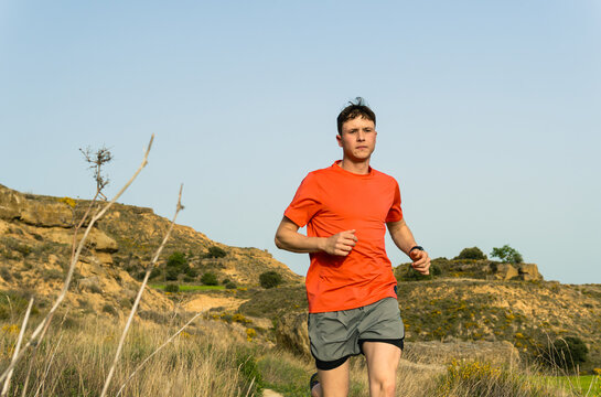 Young man trail running outdoors on a natural path