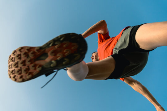 Athlete running against blue sky bottom view