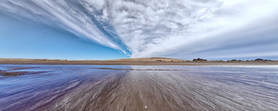 Beach tidal flat reflecting contrasting sky and clouds