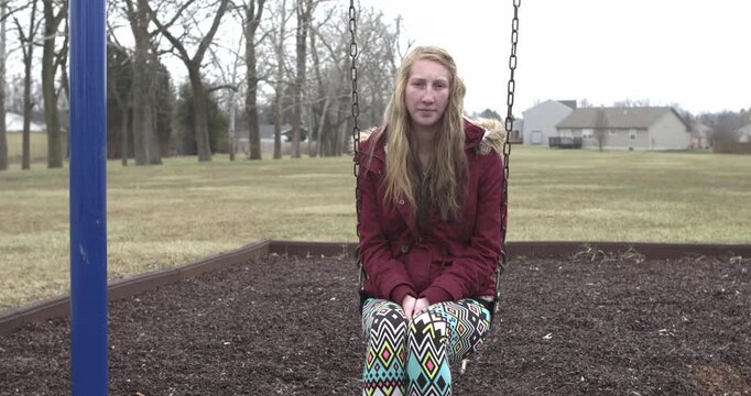 Sad and depressed girl sitting on swing 4k