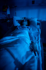 Patient resting quietly. Serene patient under gentle light. Calm individual lying peacefully in dim lighting. Tranquil patient reclined with closed eyes in soft blue glow © fotodrobik