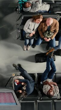 Vertical video Shouting, flight delay and angry people making annoyed phone calls in busy airport terminal, top down view. Yelling, flight cancelation and frustrated travelers upset by losing plane